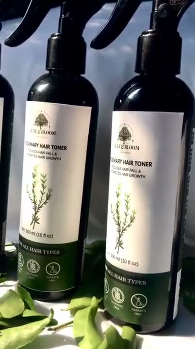 Two Rosemary Hair Toner bottles standing together with fresh leaves